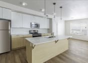 Thumbnail 6 of 7 - a kitchen with an island and a stainless steel refrigerator