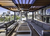 Thumbnail 3 of 7 - A wooden deck with a couch and a table.