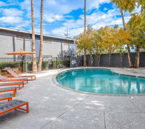 a swimming pool with benches and trees next to a building