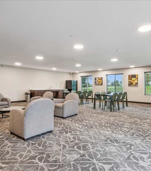 A room with grey carpet and a television on the wall.