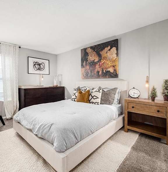 A bedroom with a large bed, a chair, and a painting on the wall.
