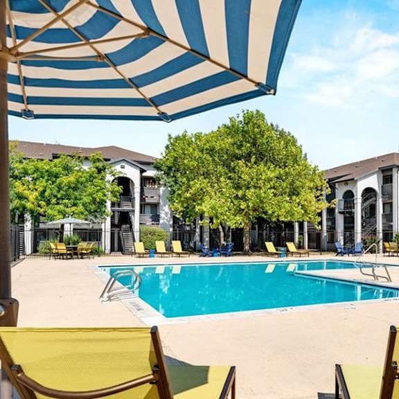 A pool surrounded by yellow chairs and umbrellas.