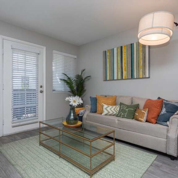 A living room with a glass coffee table and a beige couch.