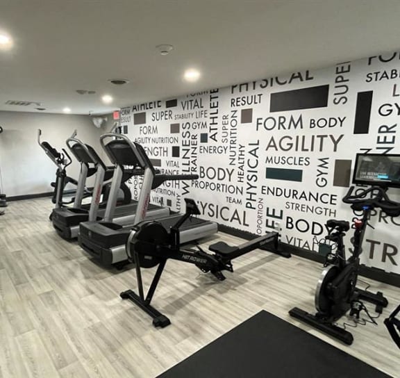 a gym with exercise machines and a wall with words on it