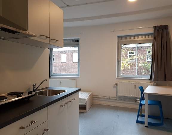 a bedroom with a bed and a desk and a window