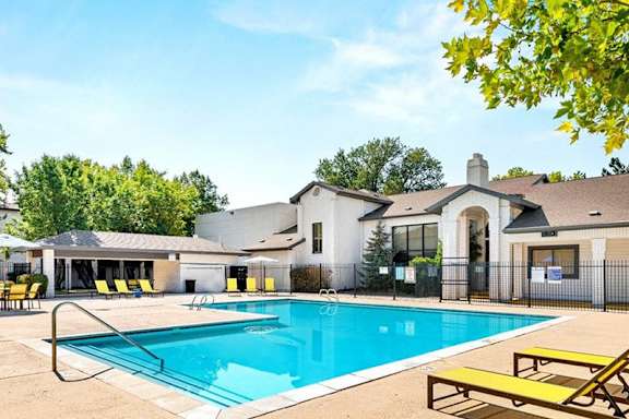 A pool surrounded by yellow chairs and umbrellas.