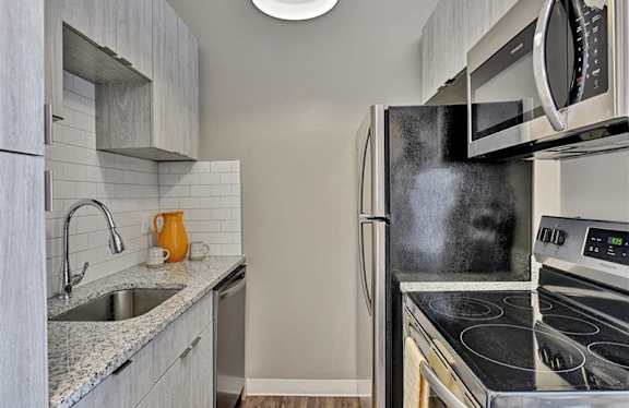A kitchen with a black refrigerator, stove, and microwave.