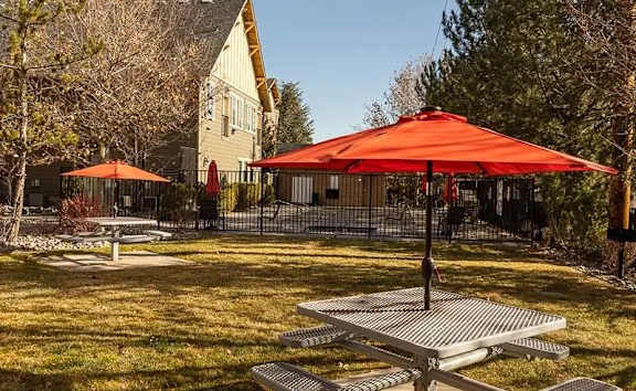 A picnic area with a red umbrella and benches.