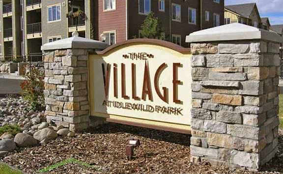 A sign for The Village at Wildwood Park in front of apartment buildings.
