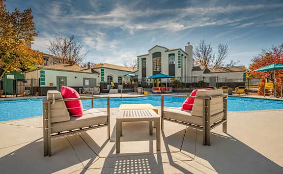 Two lounge chairs and a table are on the edge of a pool.