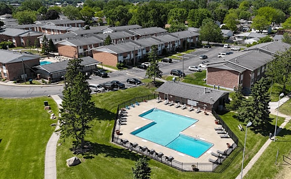 A large swimming pool surrounded by a fence and chairs in a grassy area.