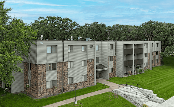 A large apartment complex with a green lawn in front.