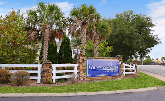 a blue and white sign sits in front of palm trees