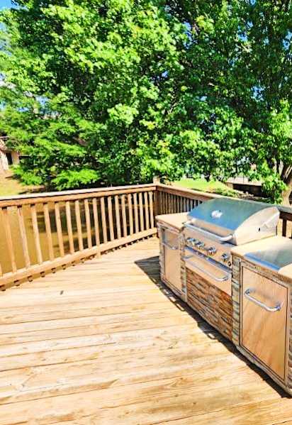 A wooden deck with a grill and a cooler on it.