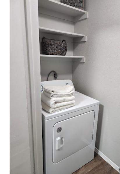 A white laundry machine is in a cabinet with towels on top.