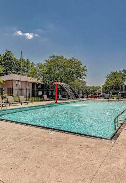 A large outdoor swimming pool surrounded by a fence and trees.