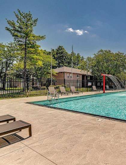 A large outdoor swimming pool surrounded by a fence and trees.