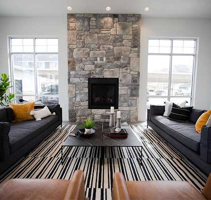 A living room with a stone fireplace and striped rug.