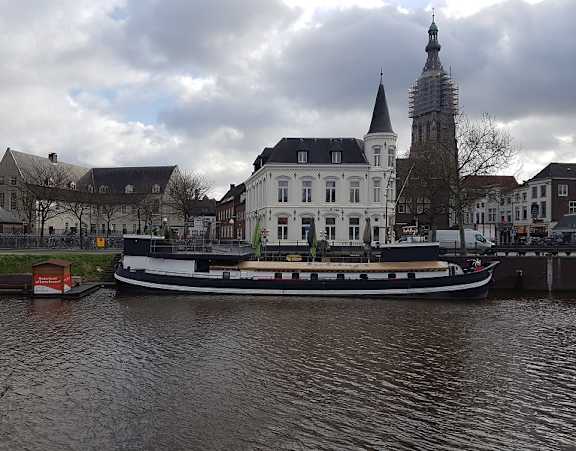 A boat is docked in front of a large white building with a tall spire.