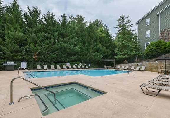 A pool surrounded by trees and chairs.