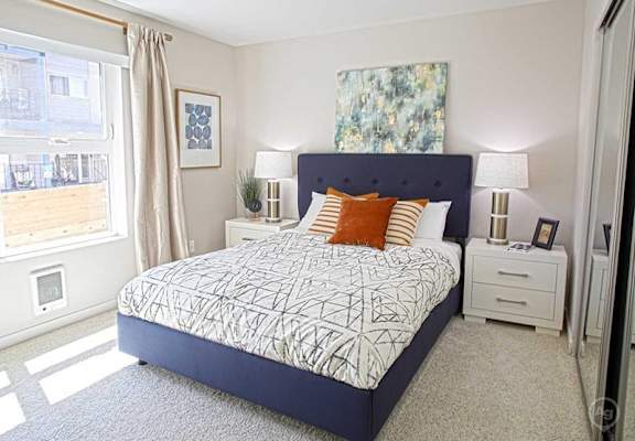 A bedroom with a large bed and a window with curtains.