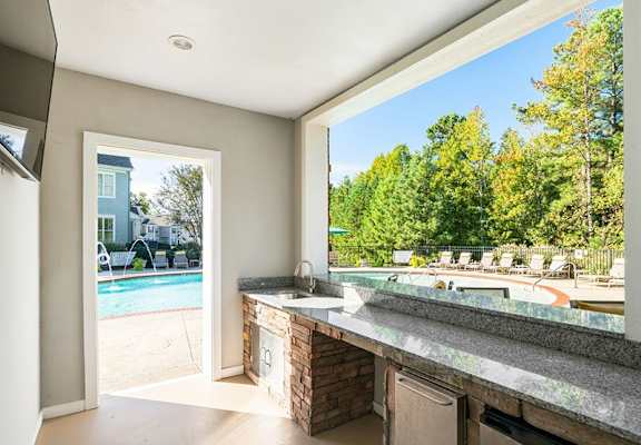 A kitchen with a view of a pool and trees.
