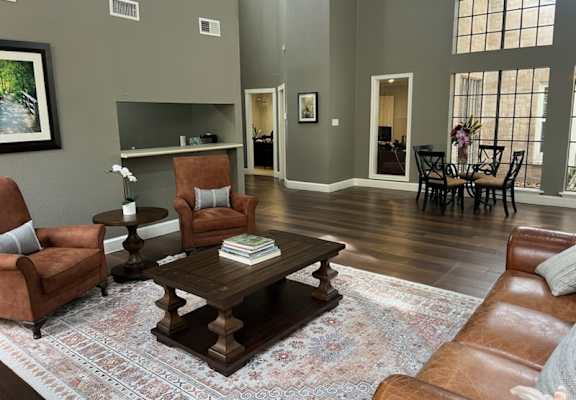 A living room with brown leather furniture and a rug.