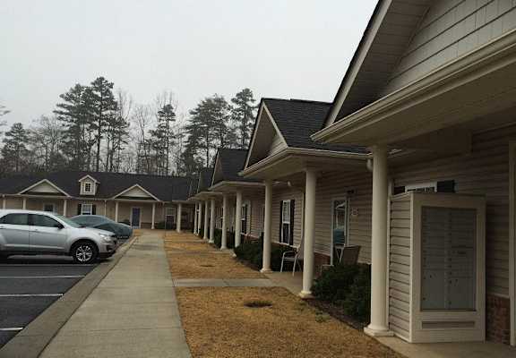 A row of houses with cars parked in front.