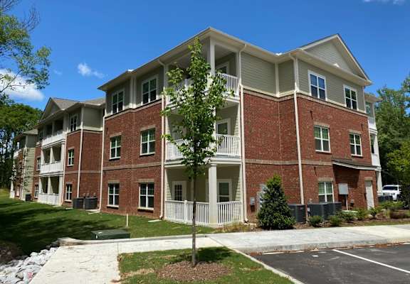 A large brick apartment building with a tree in front.