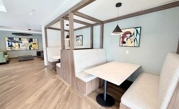 A room with a white table and chairs with a wooden floor and a wall with a painting on it.