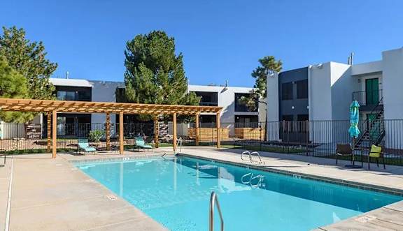 A swimming pool with a wooden pergola over it.
