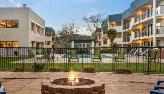 A fire pit sits in the middle of a patio surrounded by chairs and tables.