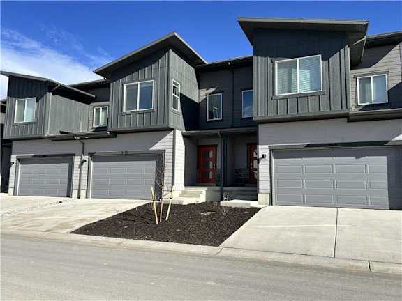 A modern house with grey siding and a red door.