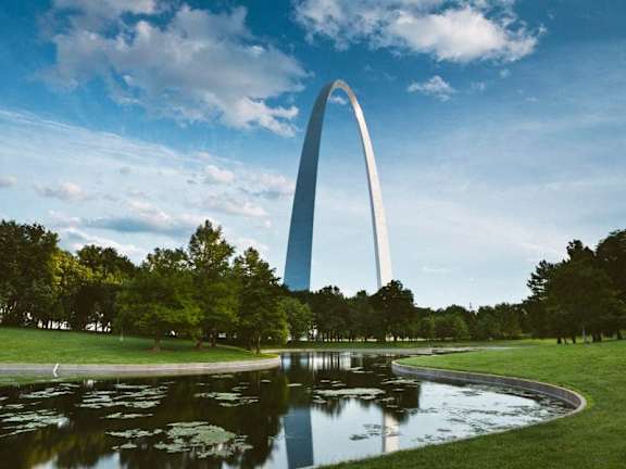 a view of the gateway arch from a park with a pond