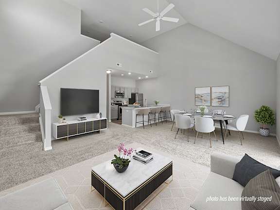 A modern living room with a television, a coffee table, and a dining table.