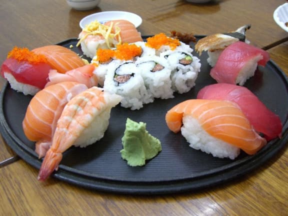 a plate of sushi on a black plate on a table