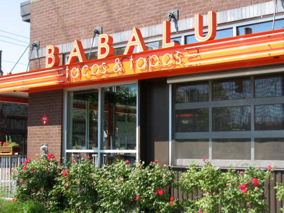 the front of a restaurant with red flowers