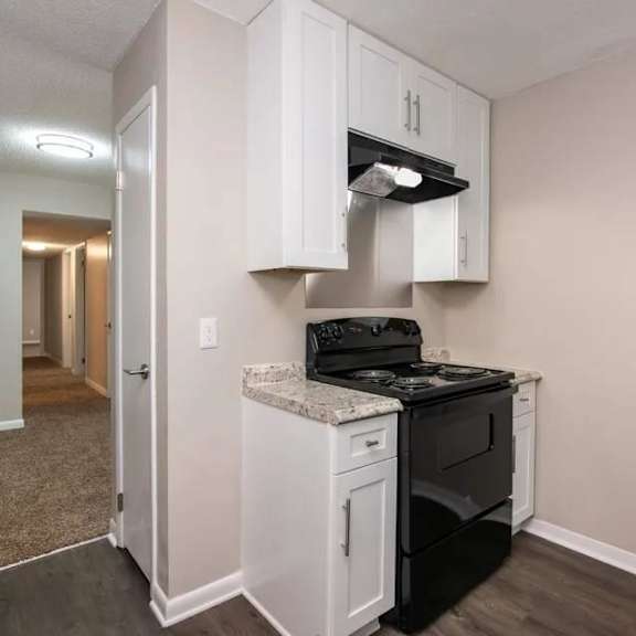 A kitchen with white cabinets and a black stove top oven. at Cleo Apartments, Athens, 35611