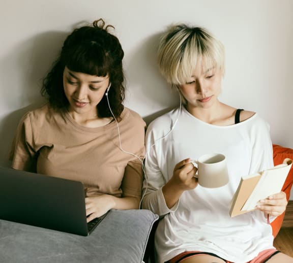 Two female students reading together.