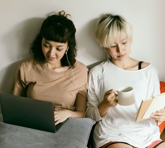 Two female students reading together.