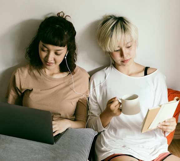 Two female students reading together.