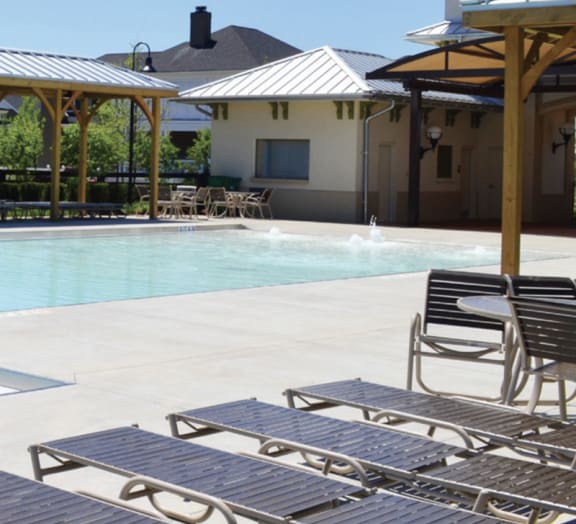 a pool with chairs and tables next to a building