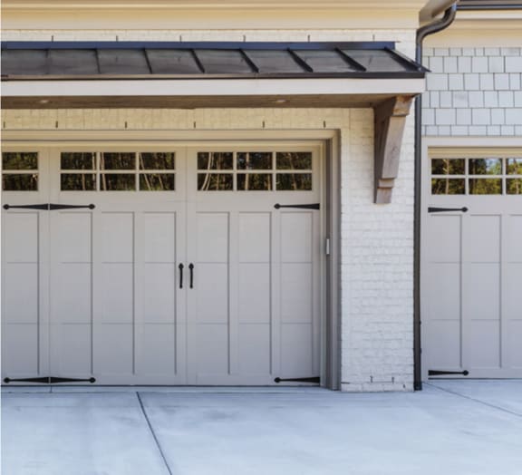 a pair of carriage style garage doors on a white brick house