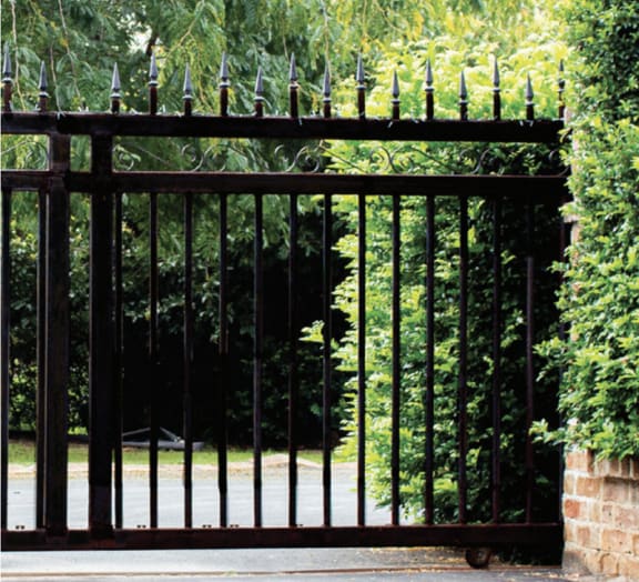 the gate to a garden with bushes behind it