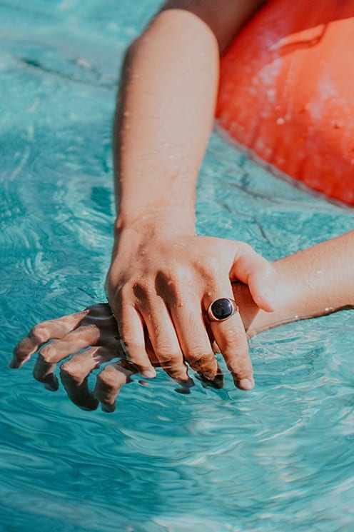 a woman sitting in a pool with her hands in the water