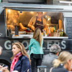 a food truck at a food festival with people sitting in front of it