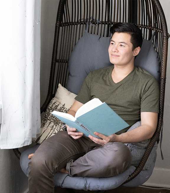 A man is sitting in a chair and reading a book.