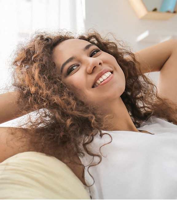 A woman with curly hair is smiling and relaxing.