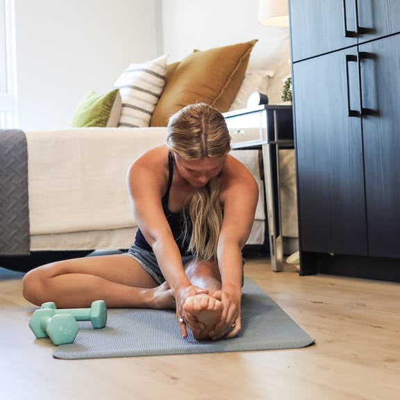woman working out and stretching in her studio apartment at citizen birmingham