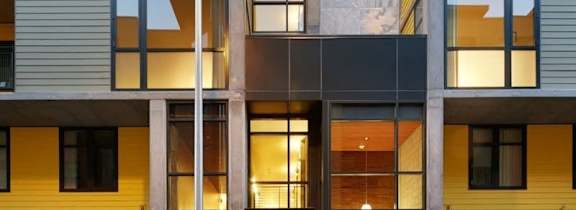 A woman is standing in the doorway of a modern building.